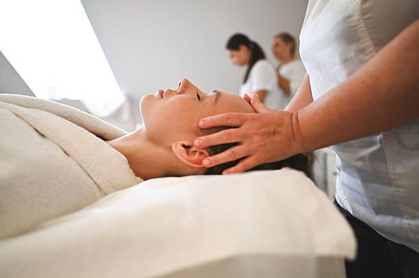 Masseuse giving relaxing head massage to young woman in spa Masseuse giving relaxing head massage to young woman in spa reiki healing stock pictures, royalty-free photos & images
